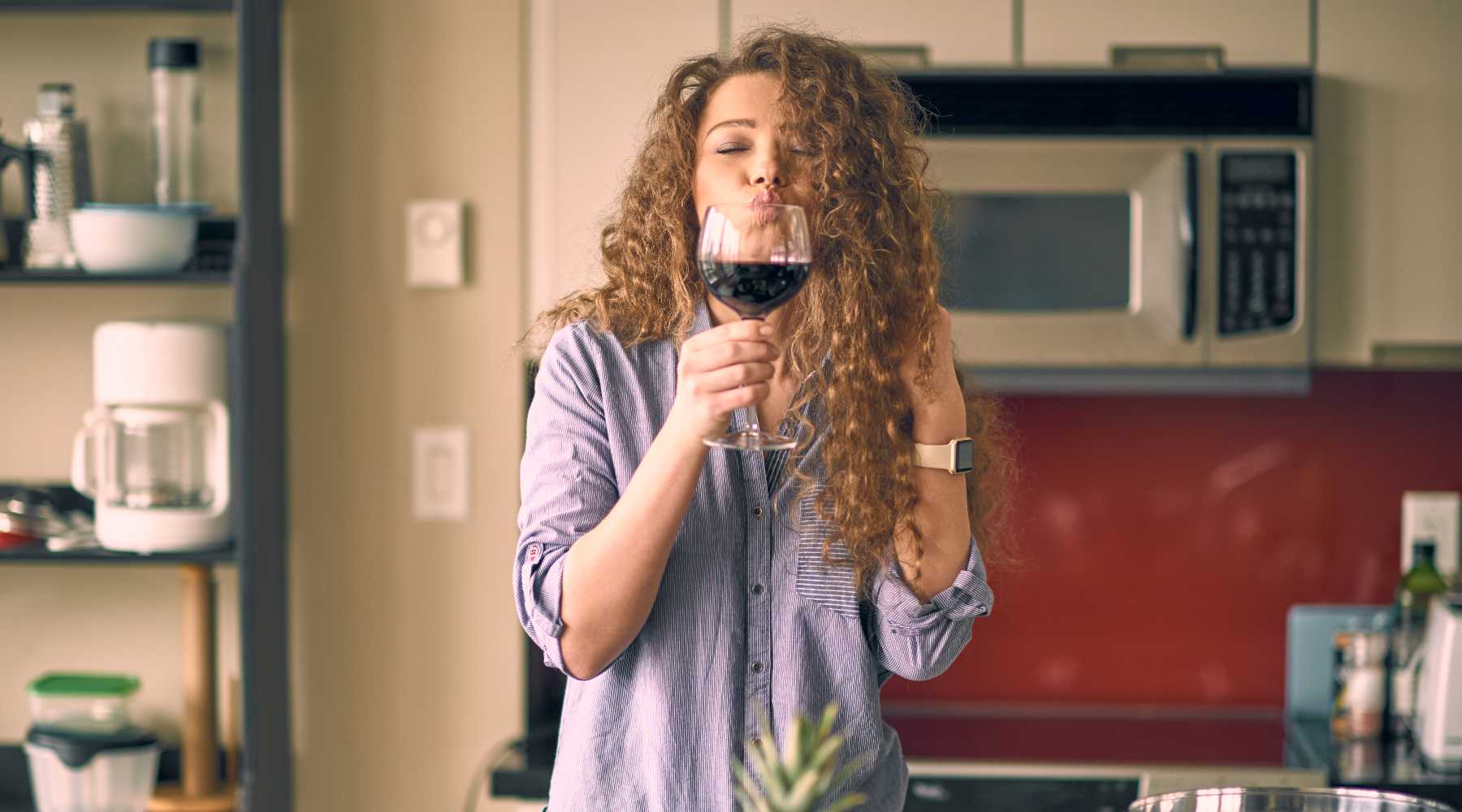 a woman smelling and tasting red wine